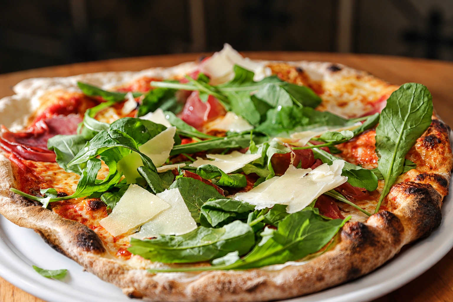 Pizza com rúcula, presunto curado e lascas de queijo.